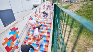 Mehrere Menschen auf einer Treppe, die mit bunten Quadraten beklebt ist.
